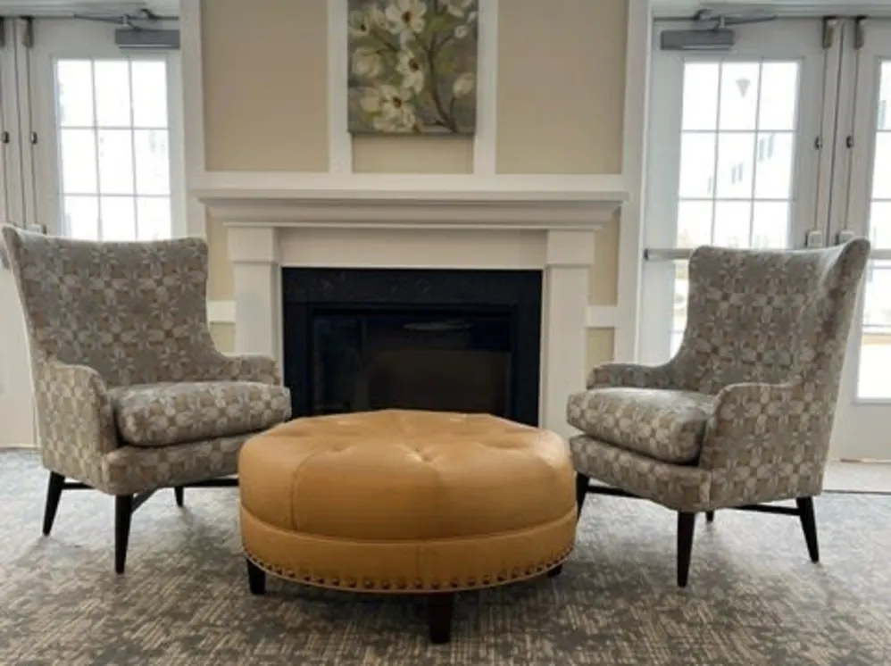 Two armchairs and leather ottoman by fireplace
