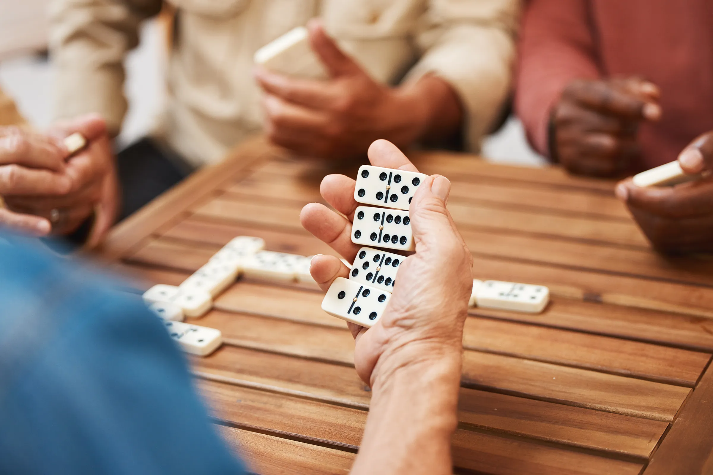 Friends playing dominoes at wooden table